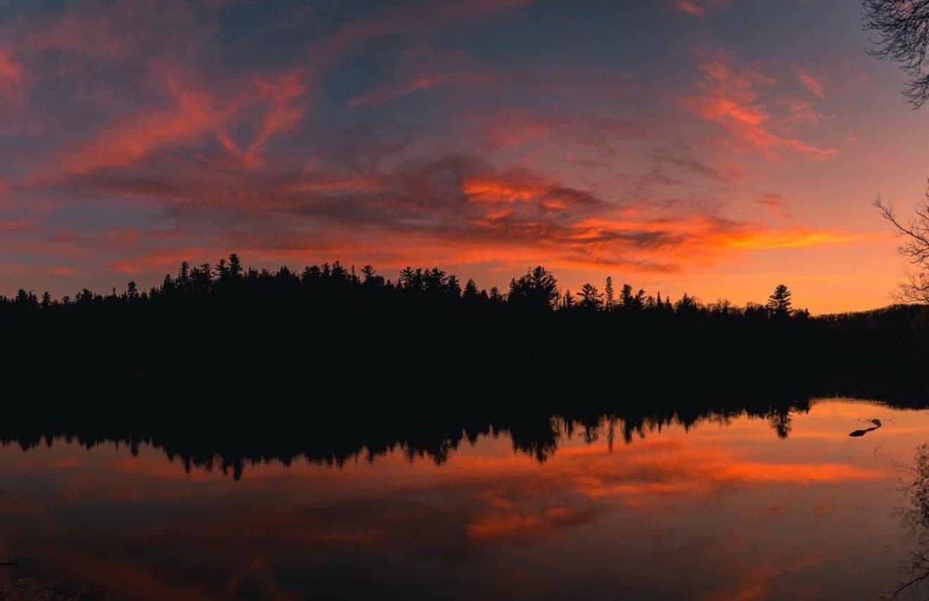 Sunset reflected in a still Northern Minnesota lake surrounded by pine forest