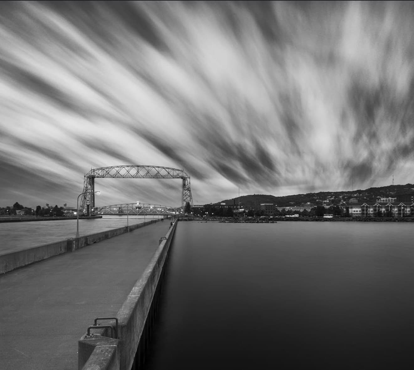 Black and white long exposure of Duluth's Aerial Lift Bridge under streaking storm clouds